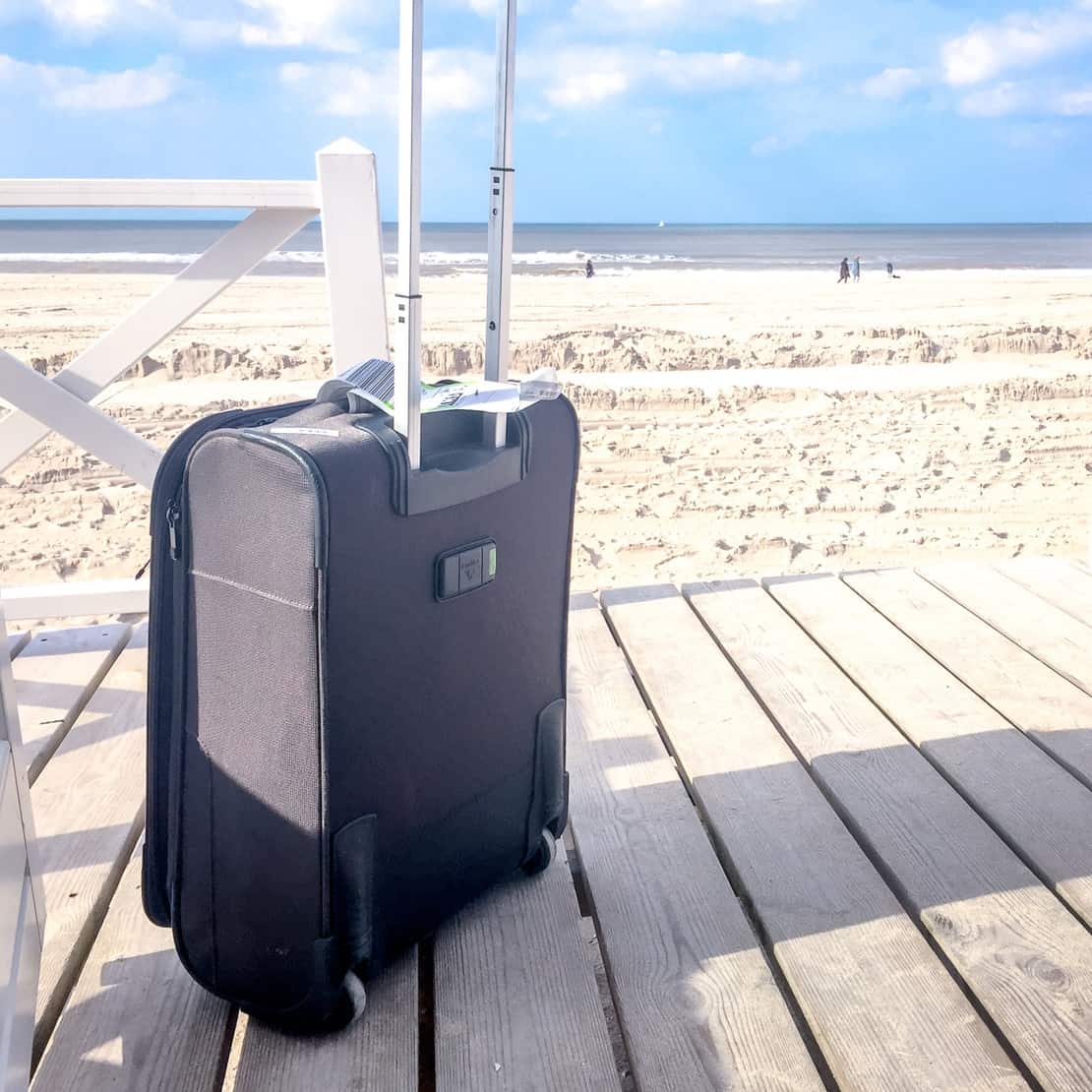 Suitcase in front of a beach - minimalist packing list 