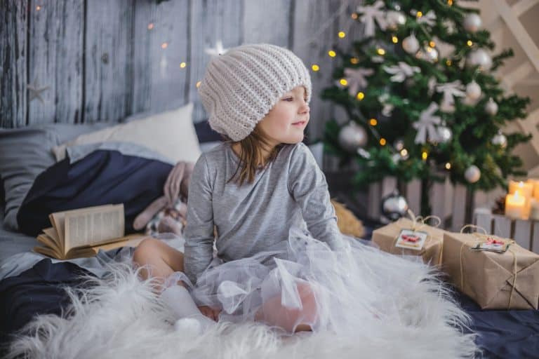 Gift Ideas for Kids - girl on rug in front of Christmas tree