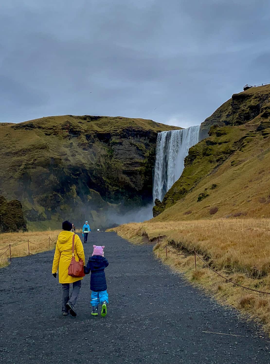 Mother and daughter approach the waterfall of Skogafoss on Iceland's south coast