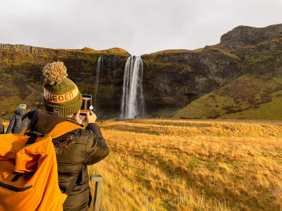 Seljalandfoss-waterfall-in-Iceland-with-woman-taking-photo