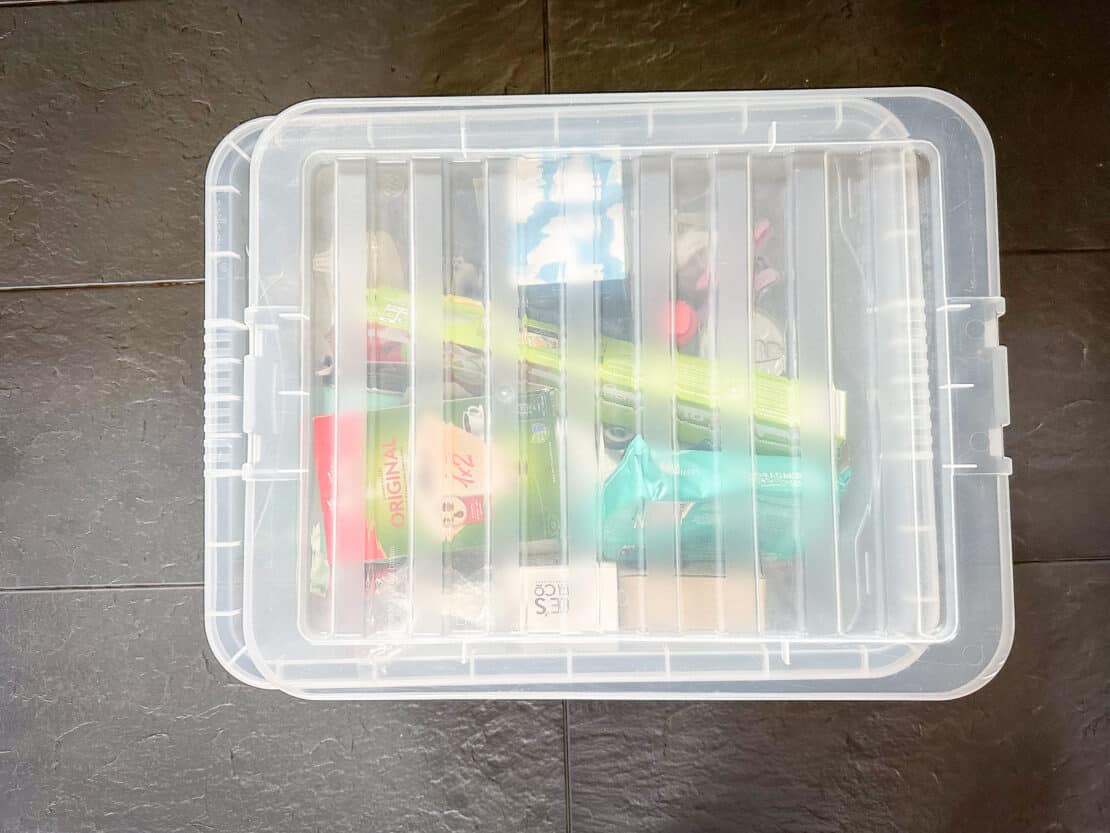 Plastic storage box with staples for a self catering trip inside like foil, wet wipes, tin opener etc