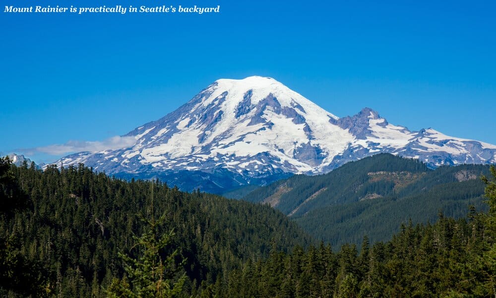 Snow-topped Mount Rainier surrounded by green forest - is Seattle worth visiting 